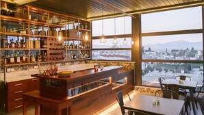 Una zona de bar con estantes de madera y un ventanal con vistas a la ciudad.