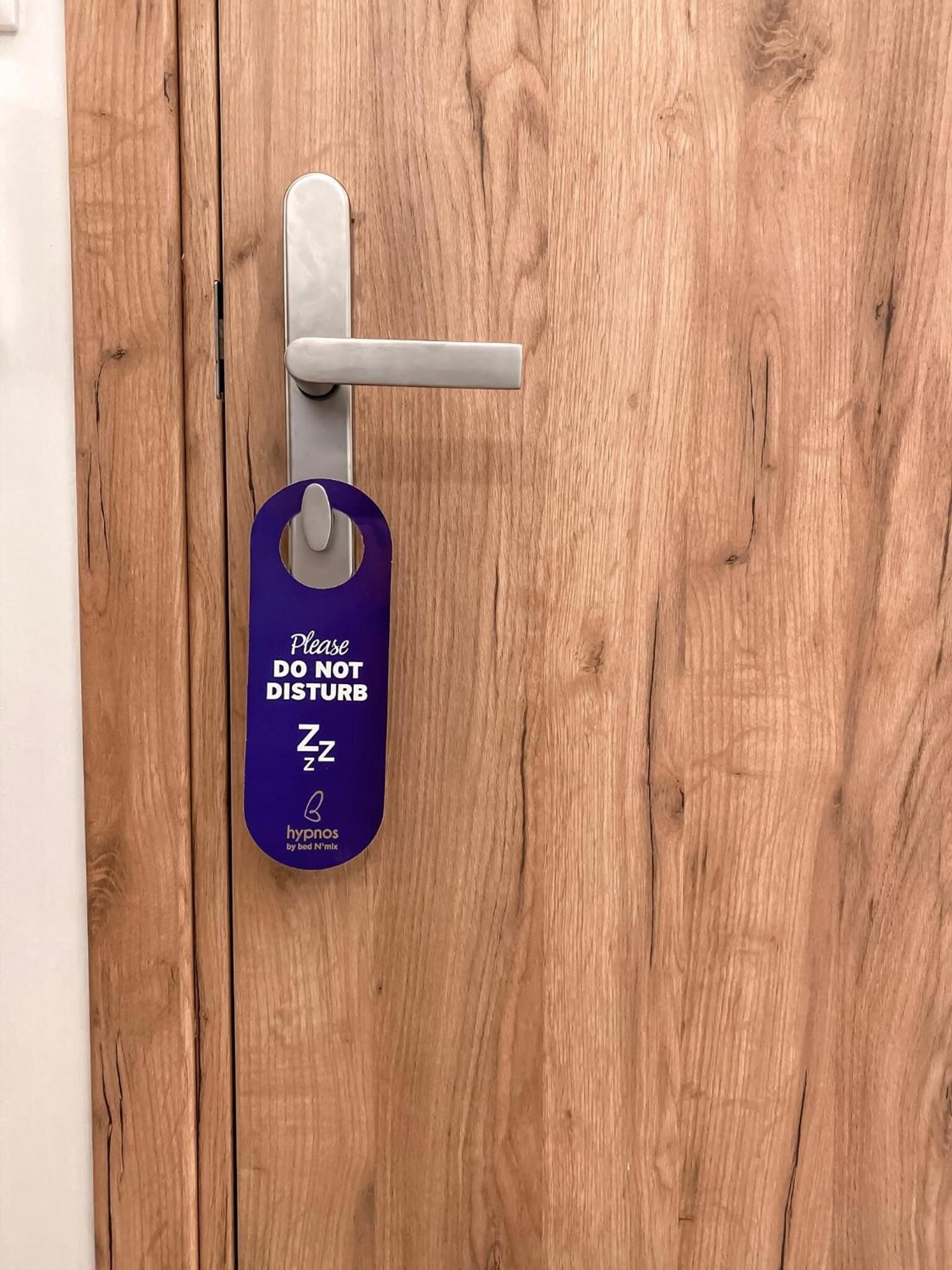 A wooden door with a keyhole and a purple tag hanging on it.