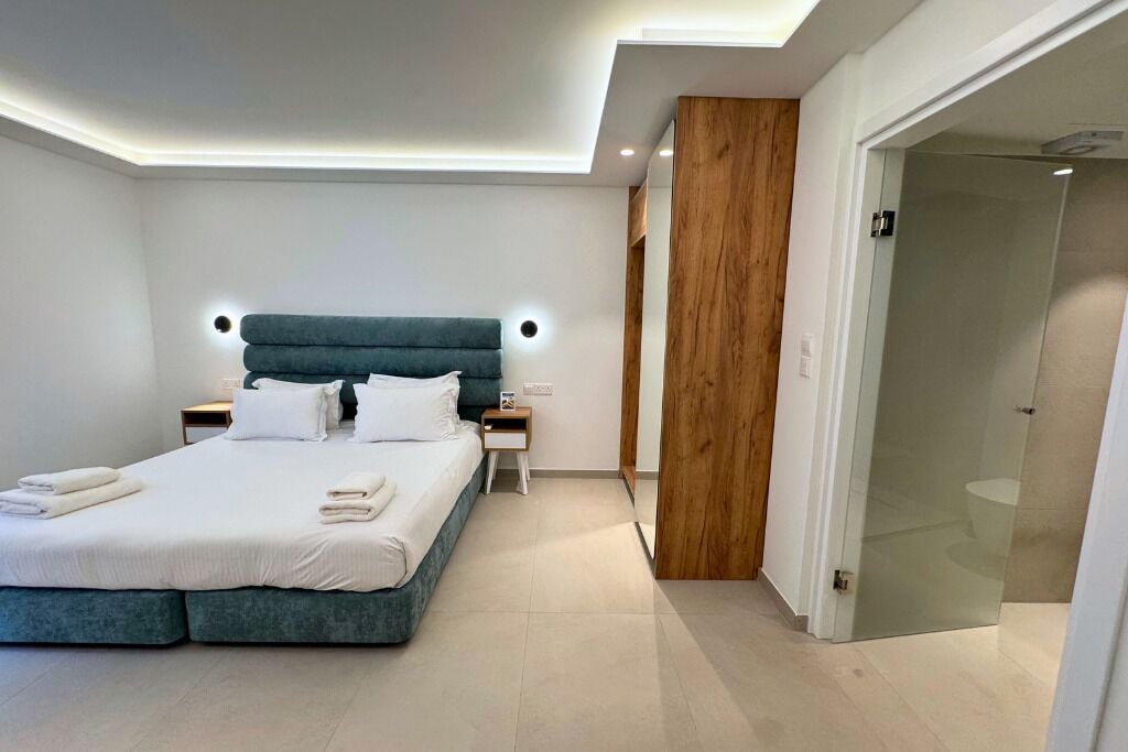 A modern bedroom with a large bed, bedside tables, and a wooden accent wall.