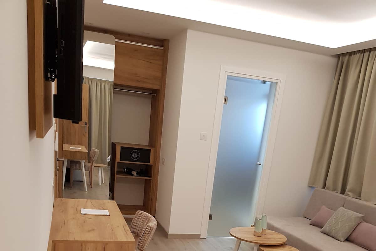 Een moderne, goed verlichte kamer met een houten bureau, een bank, een bed en een klein tafeltje.