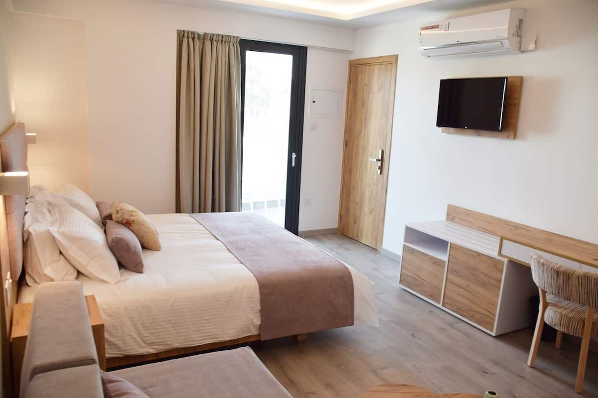 Een hotelkamer met een bed, een bureau, een stoel, een televisie en een kledingkast.