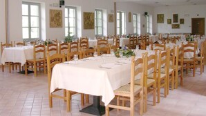 Une grande salle à manger avec de nombreuses tables et chaises, disposées en rangées.