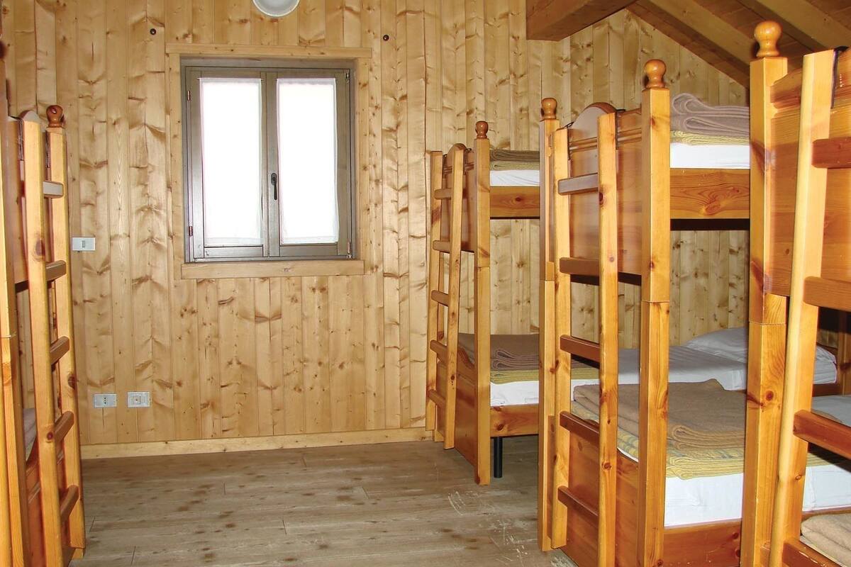 Une cabane en bois avec des lits superposés, une fenêtre et un luminaire.