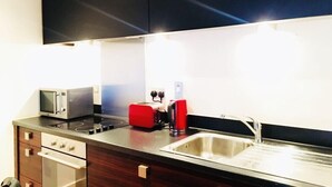 A modern kitchen with a microwave, toaster, and sink. - Birmingham Serviced Apartment- Ryland (Birmingham)