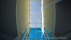 A view through a window with a grid pattern, leading to a blue pool. - Residência Angra Deep Blue (Angra dos Reis)