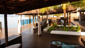A wooden deck with thatched roof seating and a view of the sea. - Residência Angra Deep Blue (Angra dos Reis)