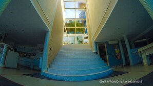 A modern hotel interior with a central staircase, large windows, and a reception desk. - Residência Angra Deep Blue (Angra dos Reis)