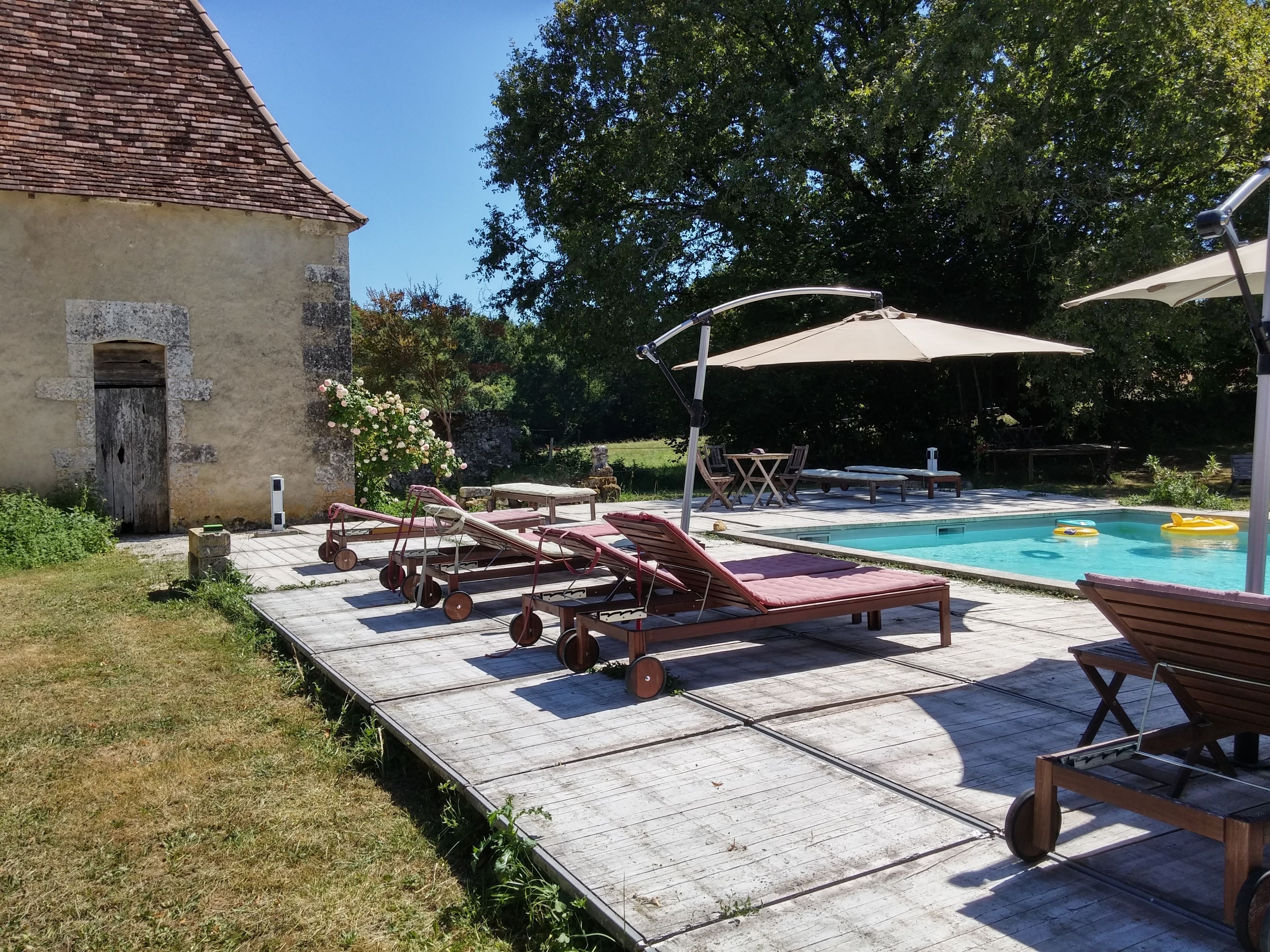 A poolside area with lounge chairs, a table, and umbrellas.