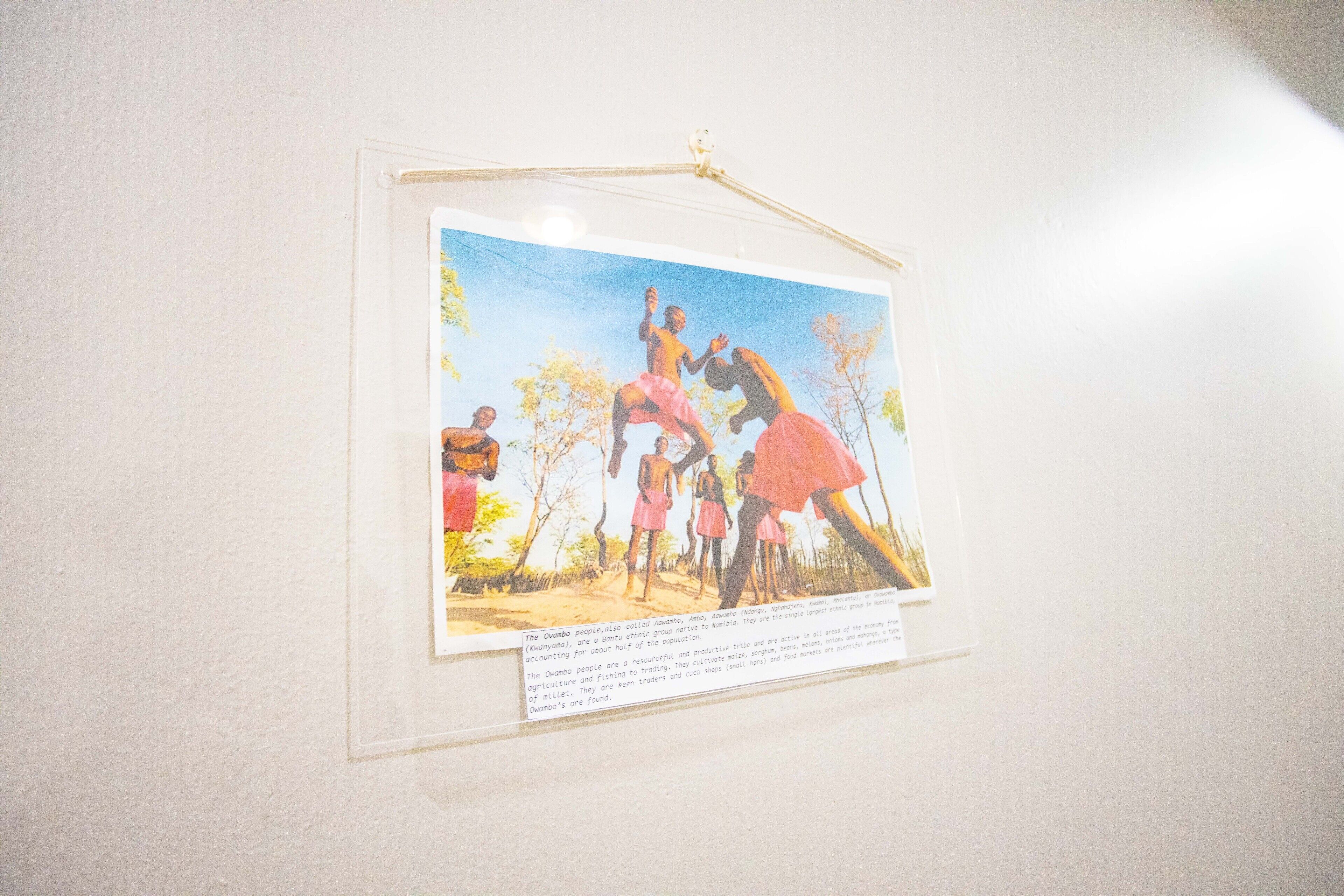 Fotografía enmarco de un grupo de personas vestidas con atuendo tradicional, colgada en una pared.