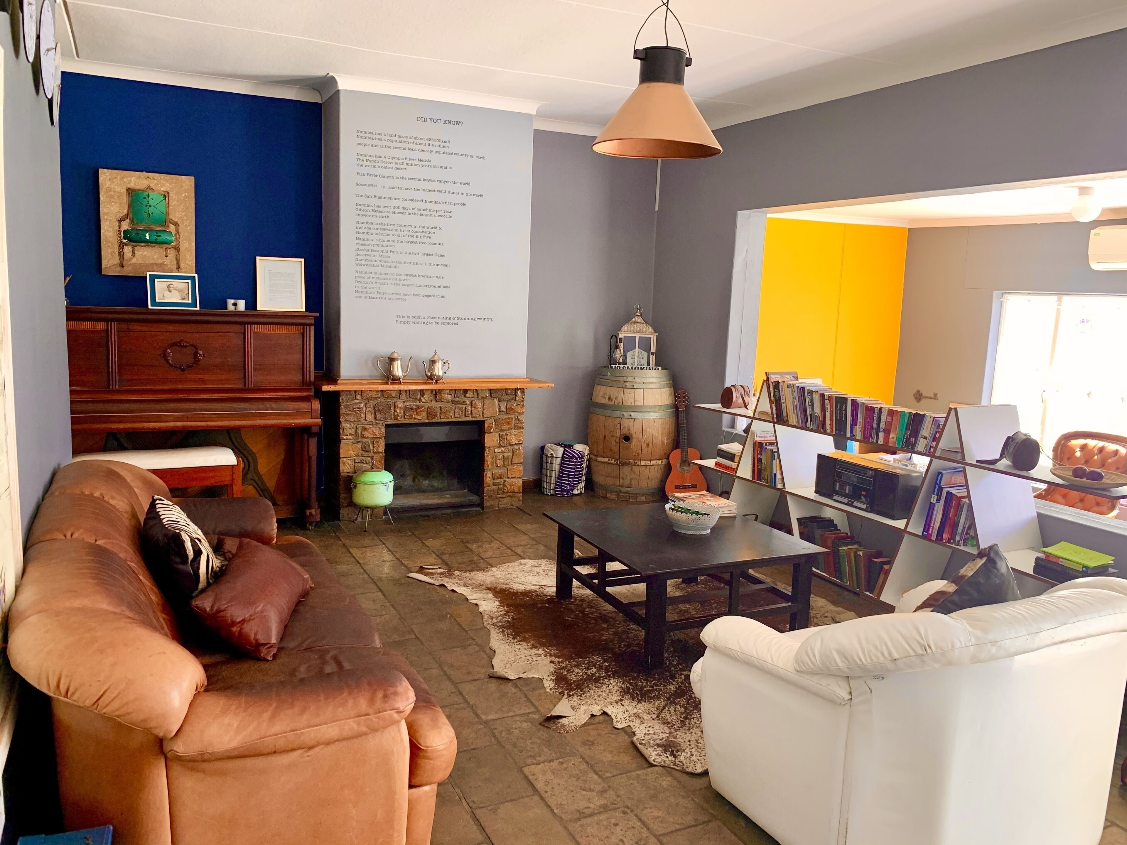 Una sala de estar acogedora con chimenea, sofás de cuero, una mesita de centro y una estantería llena de libros.