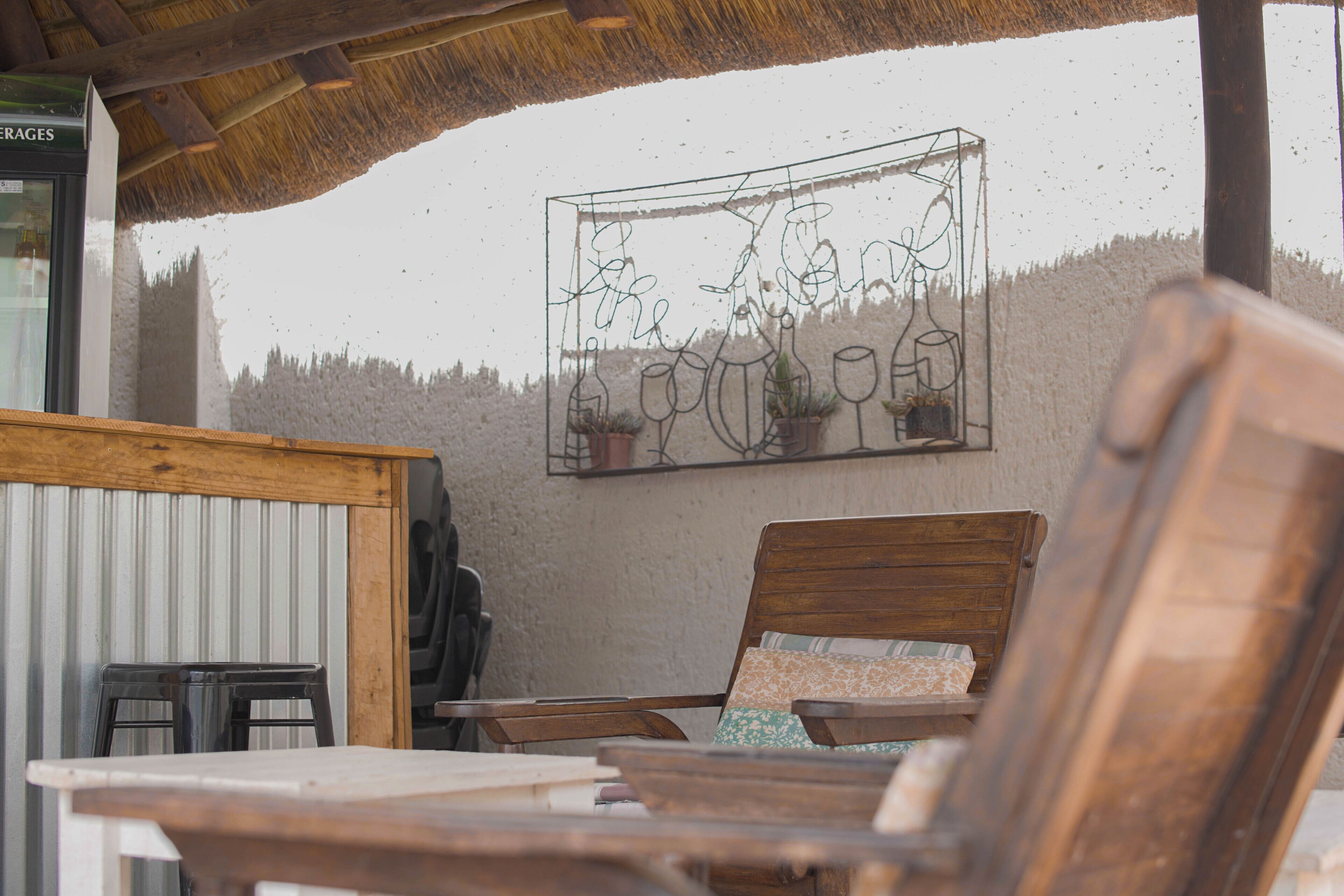 A rustic outdoor seating area with wooden furniture and a decorative wall art piece.
