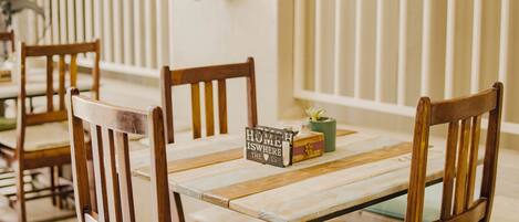 Un comedor con sillas de madera y una mesa, un libro titulado "HOME IS WHERE THE HEART IS" y un pequeño jarrón con una planta.