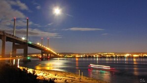 A nighttime view of a bridge with lights reflecting on the water. - North Kessock Hotel (Inverness)
