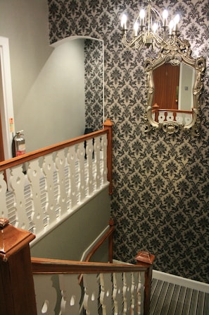 A staircase with ornate white railings and a chandelier above. - North Kessock Hotel (Inverness)