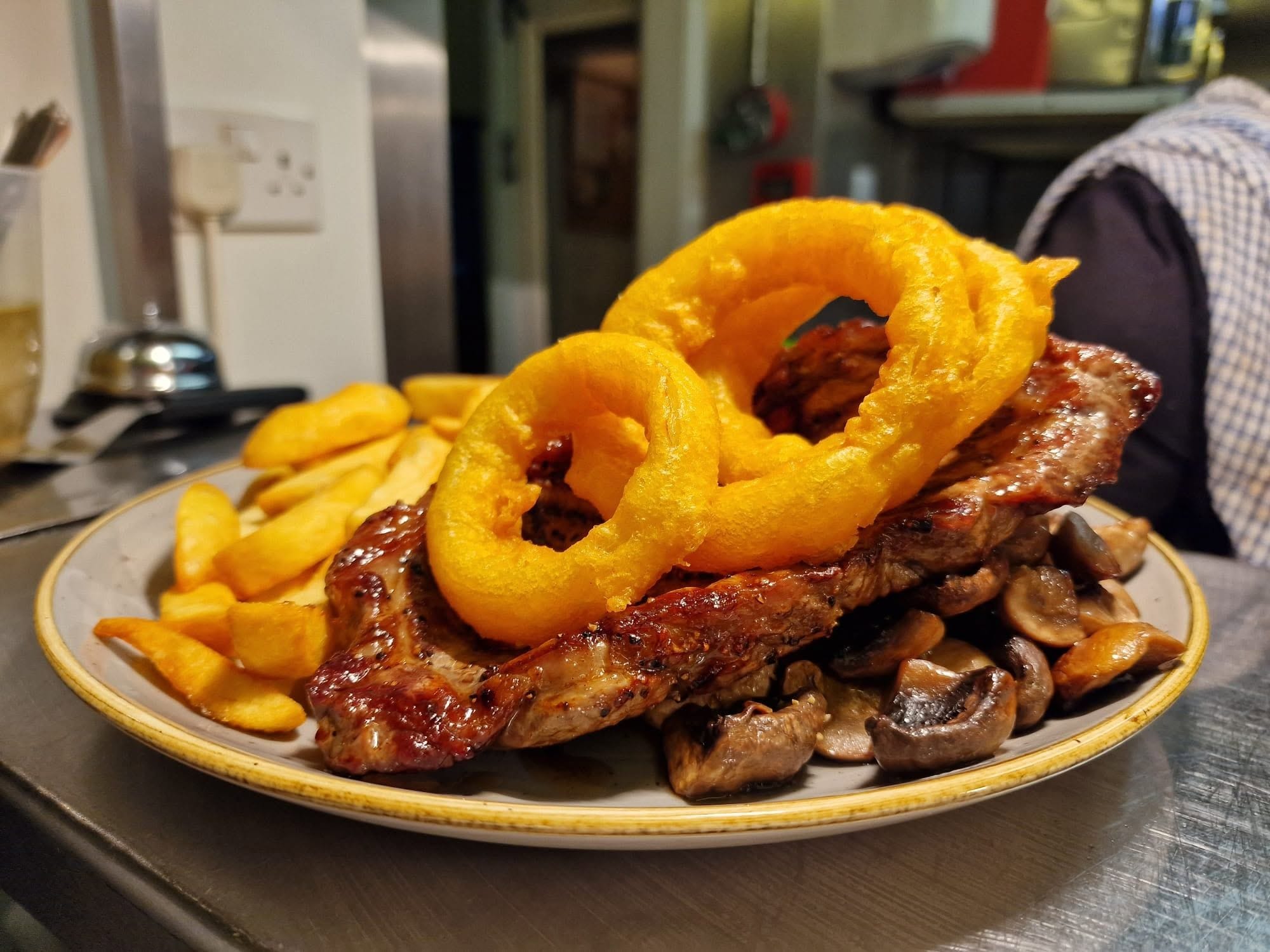 A plate with grilled meat, mushrooms, and onion rings.