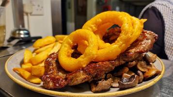 A plate with grilled meat, mushrooms, and onion rings.