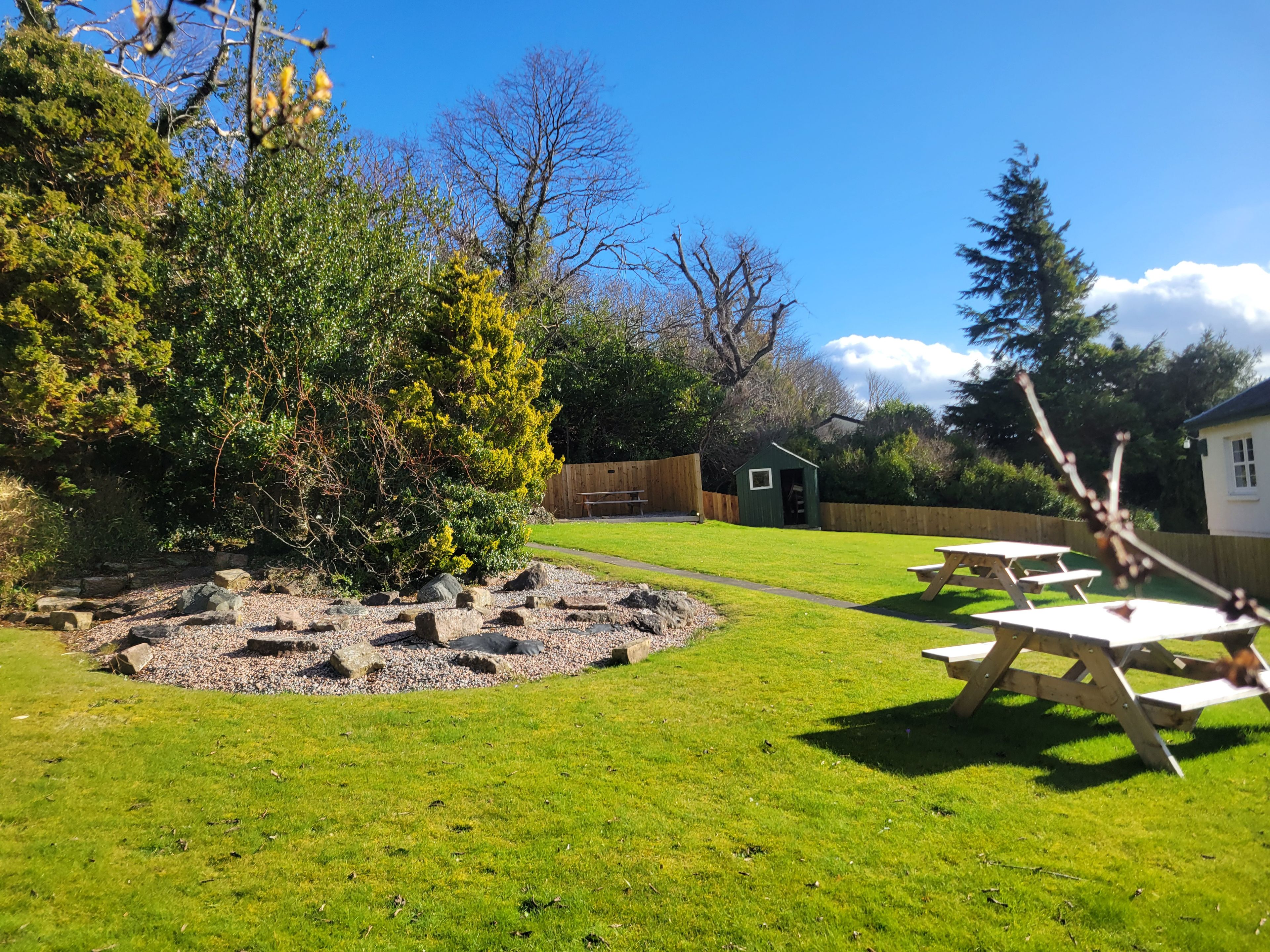 A well-maintained grassy area with picnic tables and a small shed.