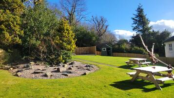 A well-maintained grassy area with picnic tables and a small shed.