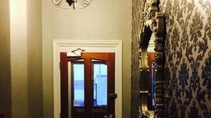 Un corridoio con una porta in legno, un lampadario e carta da parati decorata.
