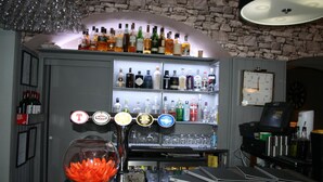 A bar area with shelves of liquor bottles, a fishbowl, and a clock on the wall. - North Kessock Hotel (Inverness)
