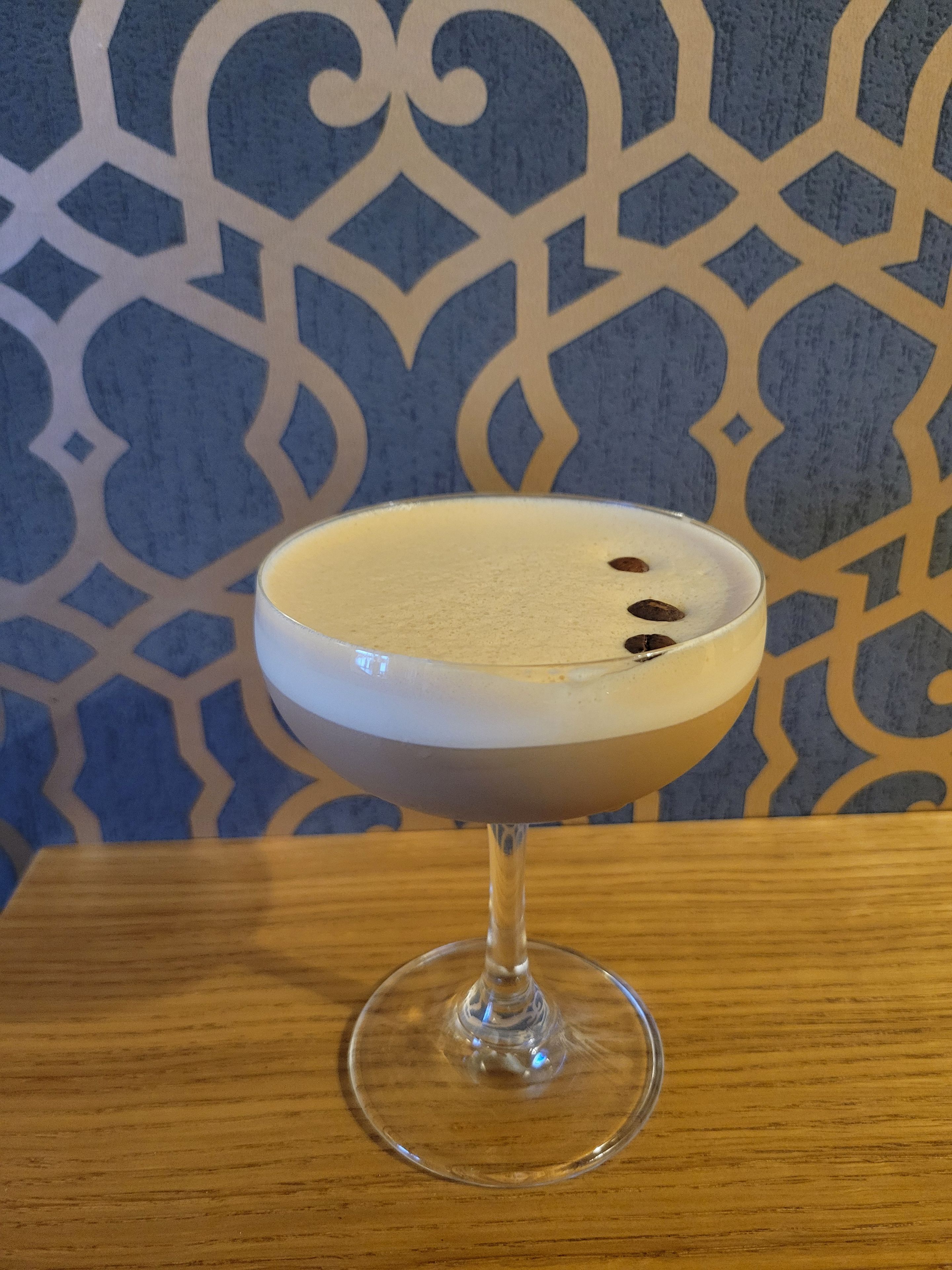 Un vaso transparente con una bebida cremosa sobre una superficie de madera.