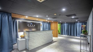 A hotel reception area with a marble counter, wooden paneling, and blue curtains. - Hotel Cloud Arena-Daan (Taipei)