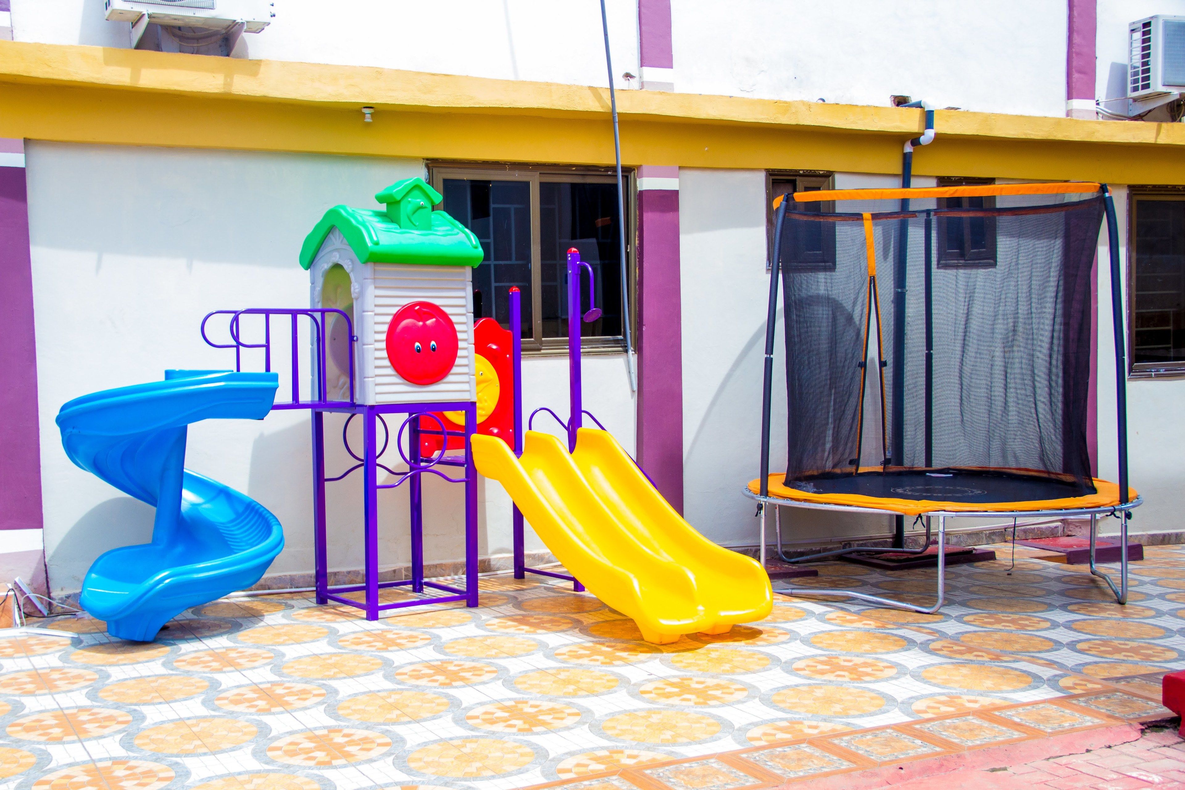 A children's play area with a slide, a climbing structure, and a trampoline.
