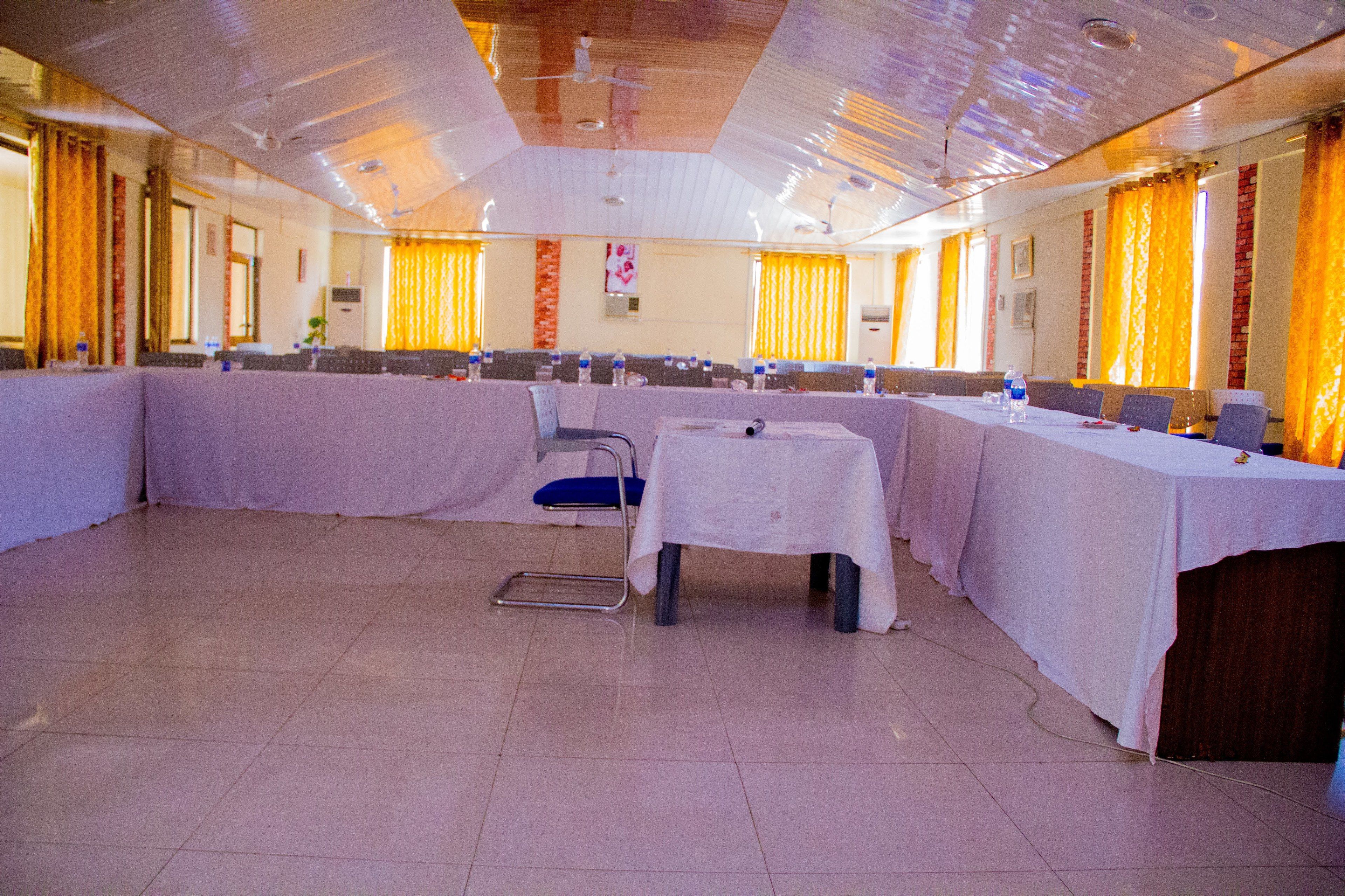 A conference room with a high ceiling, white tables, and blue chairs.