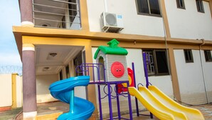 A playground with slides and a climbing structure in front of a building. - Glamossay Hotel (Sunyani)