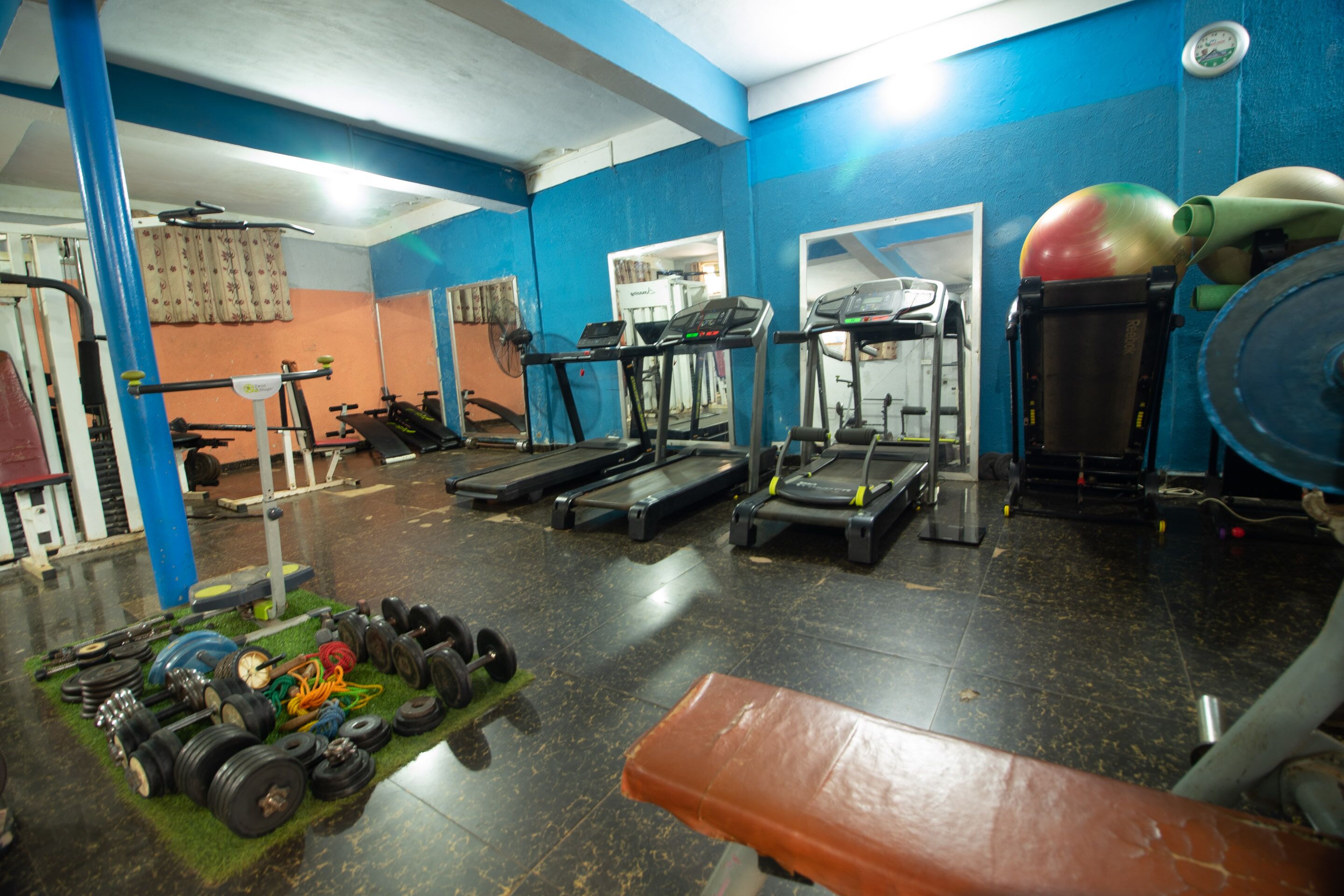 Un gimnasio con cintas de correr, máquinas de pesas y pesas sueltas.