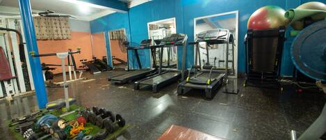 Un gimnasio con cintas de correr, máquinas de pesas y pesas sueltas.