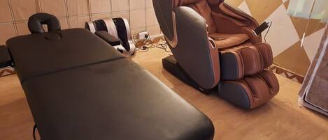 A massage therapy room with a massage table and a massage chair.
