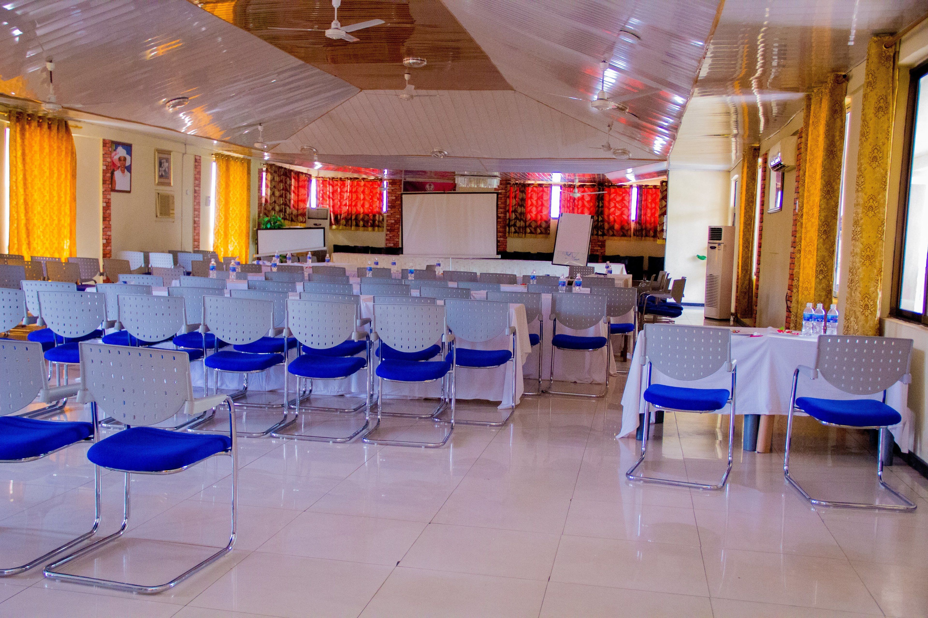 A conference room with rows of chairs, a whiteboard, and a stage.