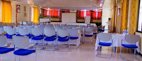 A conference room with rows of chairs, a whiteboard, and a stage.