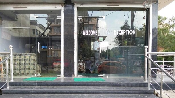 A reception area with a glass door, a sign reading "WELCOME RECEPTION", and a staircase leading up to it. - Hotel Mohit Palace (Jaipur)