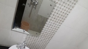 A bathroom with a white sink, toilet, and a mirror above the sink. - Hotel Mohit Palace (Jaipur)
