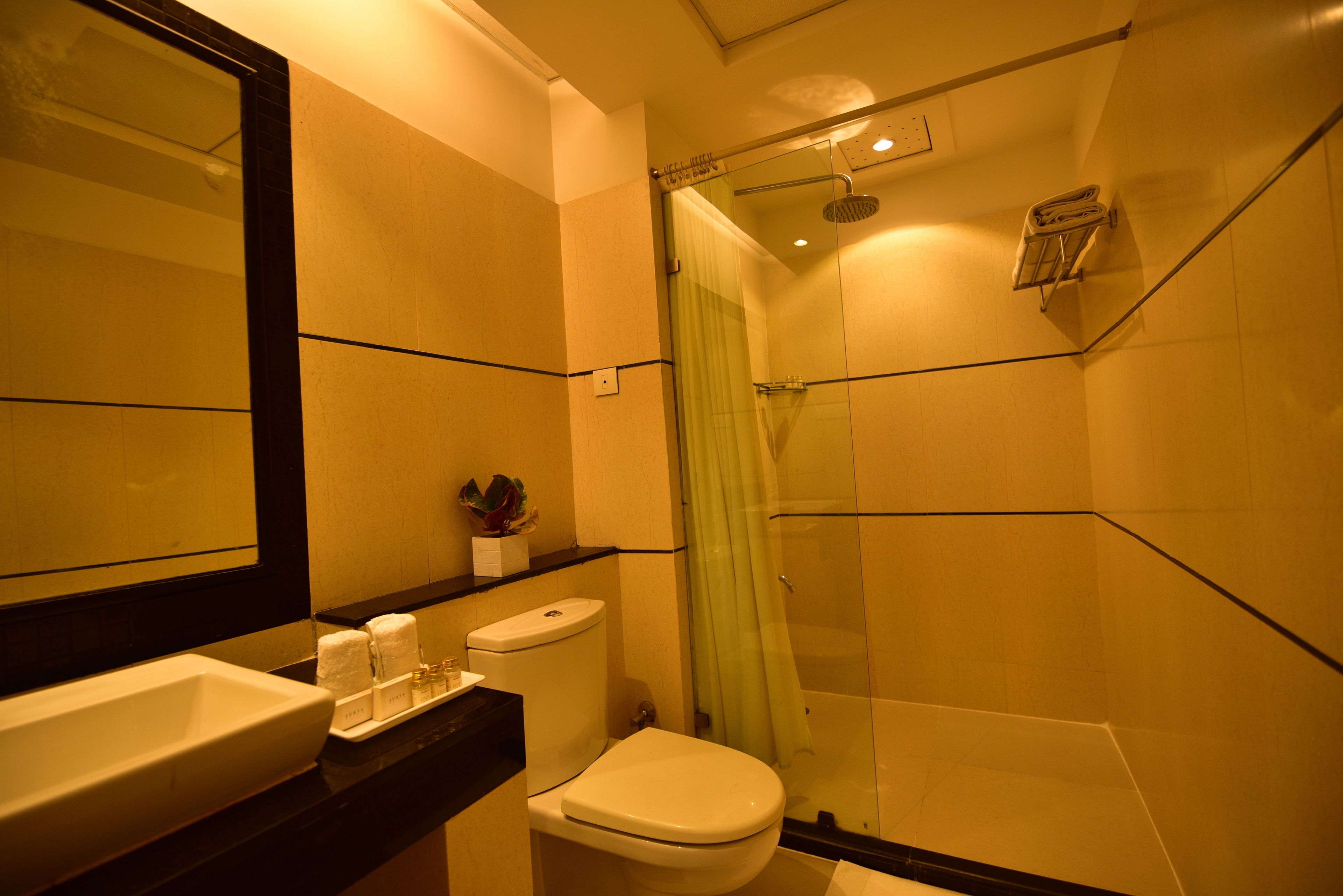 A modern bathroom with a large mirror, a sink, a toilet, and a glass-enclosed shower.