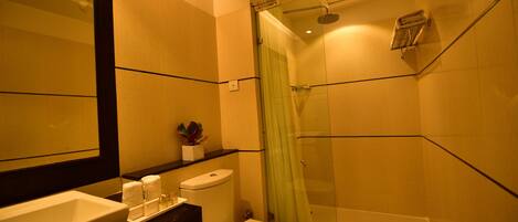 A modern bathroom with a large mirror, a sink, a toilet, and a glass-enclosed shower.
