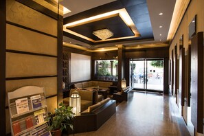 A modern lobby with a reception desk, seating area, and large windows. - Hotel Surya Royal (Kota)