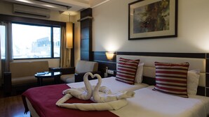 Una habitación de hotel con una cama, un sofá, un escritorio y un ventanal grande.