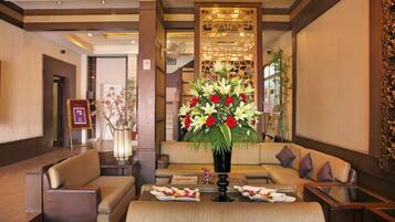 Un vestíbulo con un sofá, una mesa con arreglos florales y una pared decorativa.