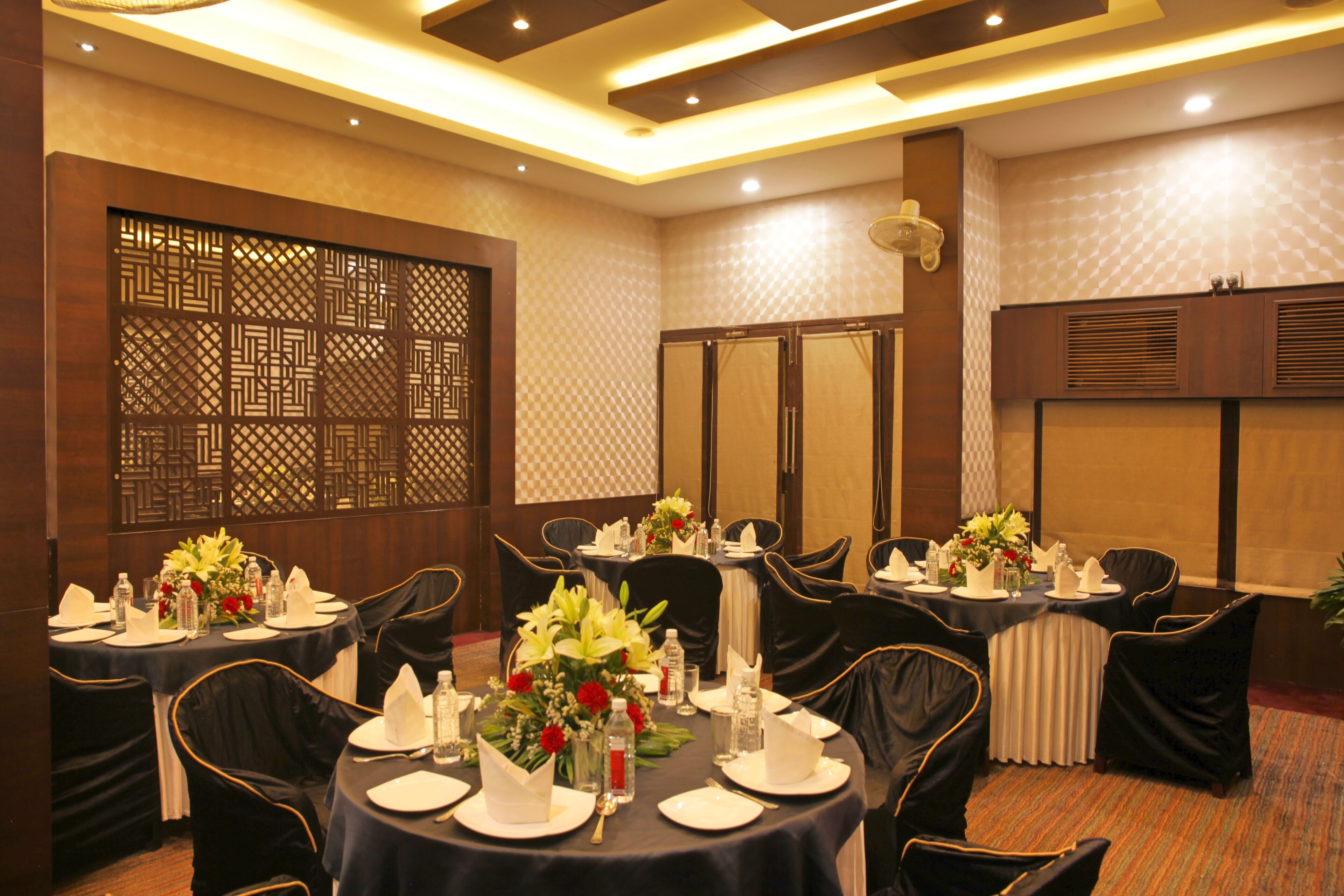 A conference room with round tables, black chairs, and floral centerpieces.