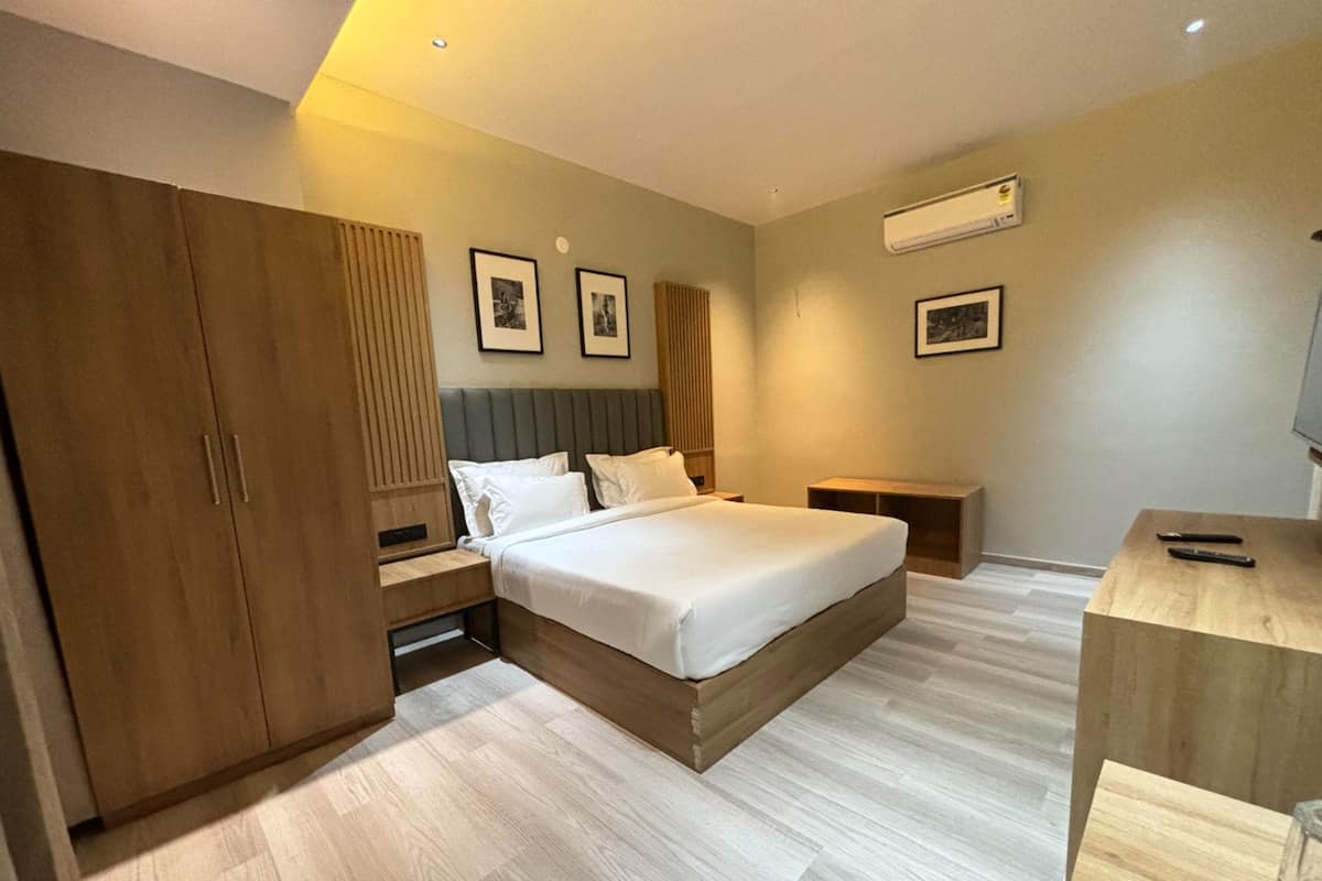 A modern bedroom with a large bed, wooden wardrobe, bedside tables, and framed pictures on the wall.