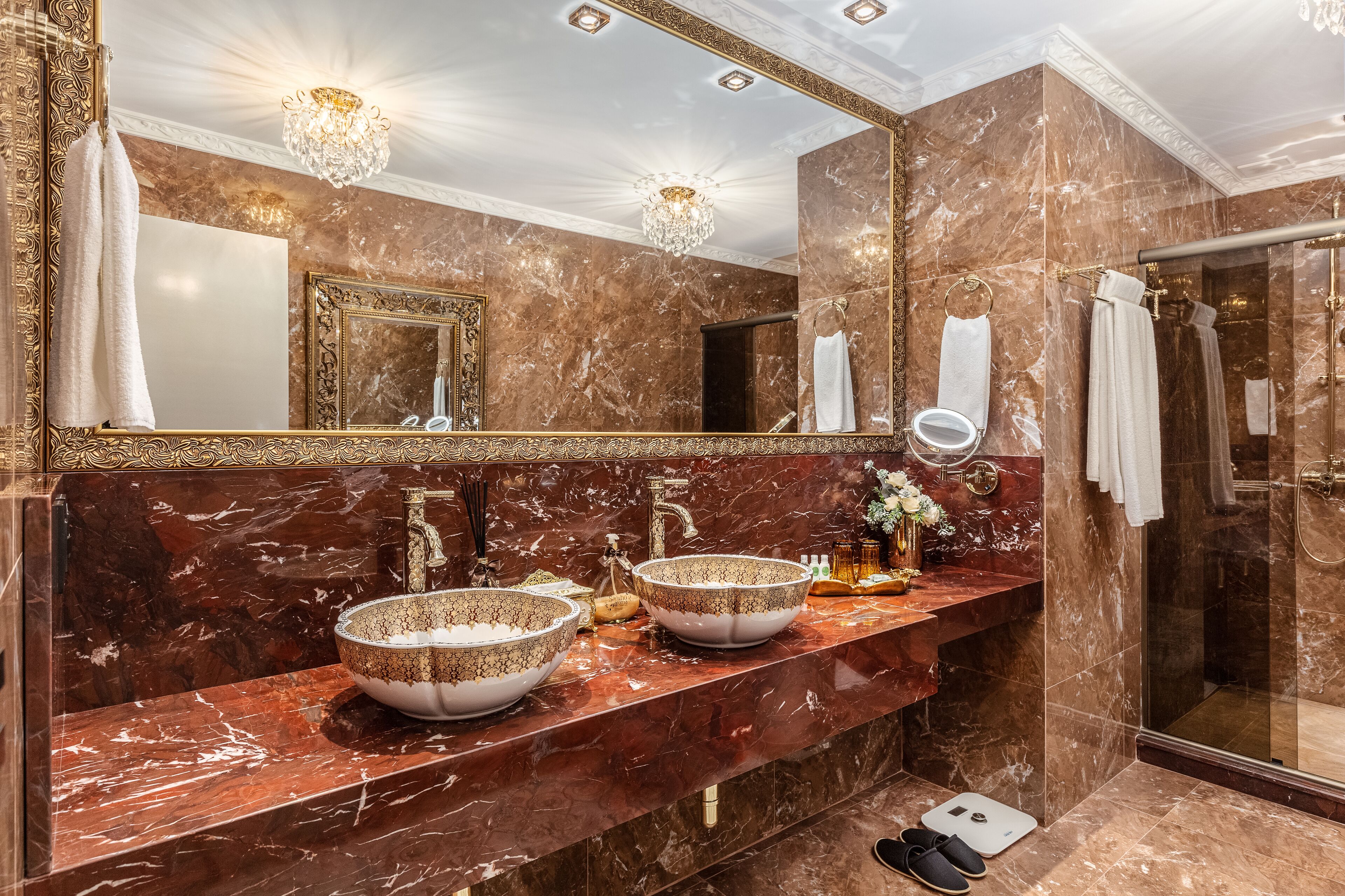 A luxurious bathroom with two large marble sinks, a large mirror, and a shower area.