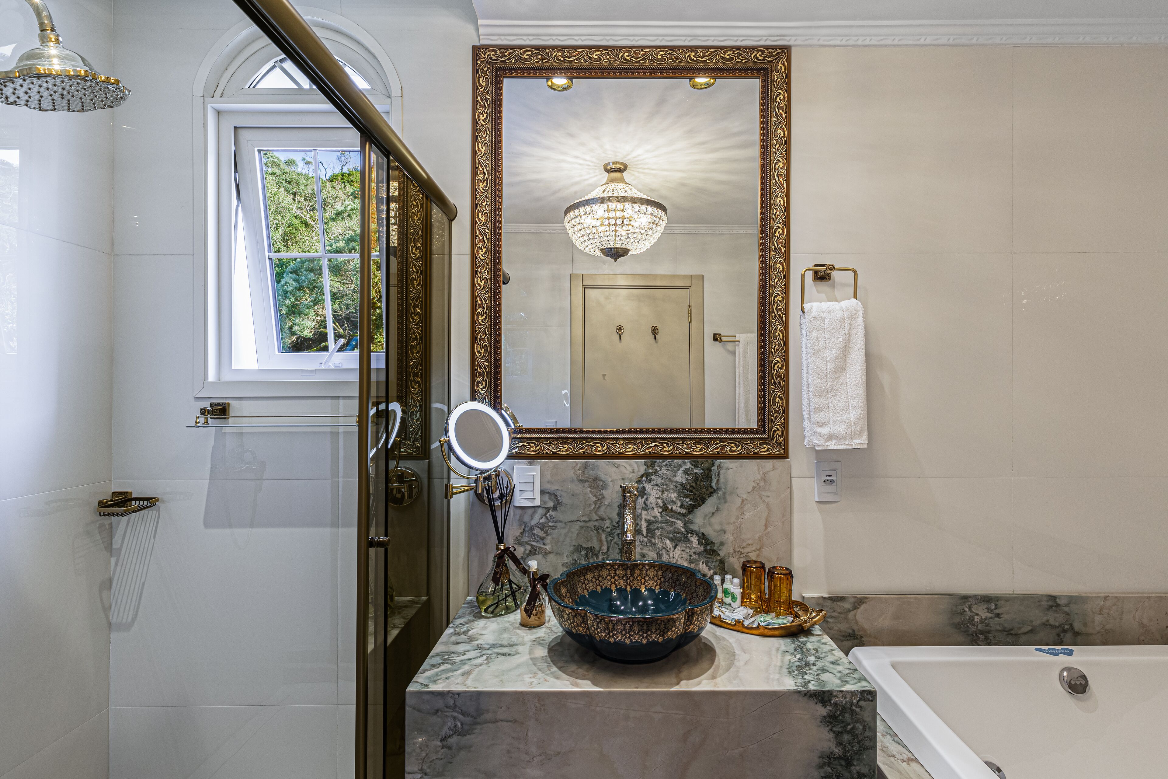 Un baño con un espejo grande, un lavabo con un cuenco decorativo, una bañera y una zona de ducha.