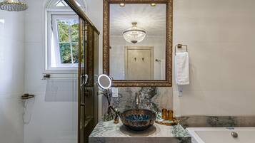Un baño con un espejo grande, un lavabo con un cuenco decorativo, una bañera y una zona de ducha.