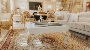 A luxurious living room with ornate furniture, a white sofa, and a coffee table with books.