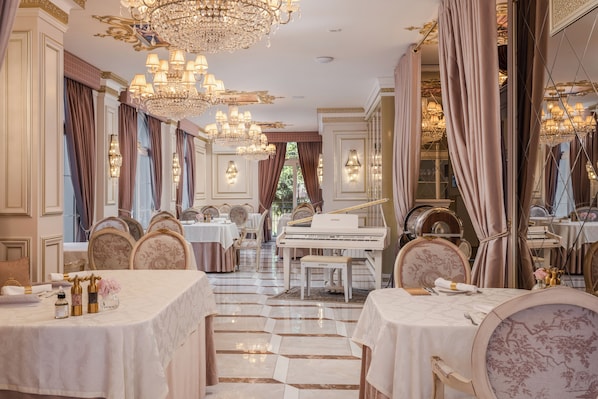 Une salle à manger luxueuse, agrémentée de lustres, d’un magnifique piano à queue et d’une décoration de table élégante.