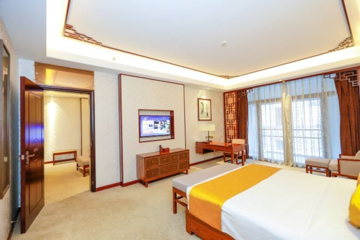 Une chambre d’hôtel avec un grand lit, un bureau, une chaise, une télévision et une armoire.