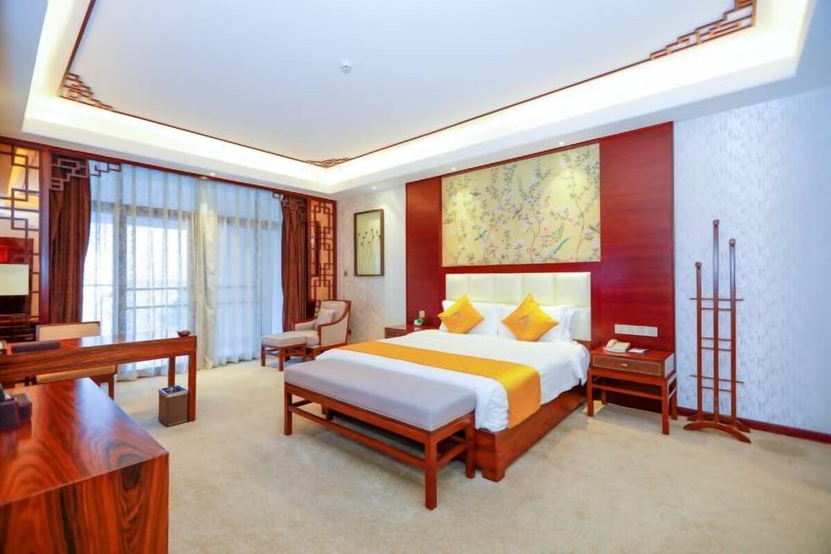 A hotel room with a large bed, bedside tables, a desk, and a chair.